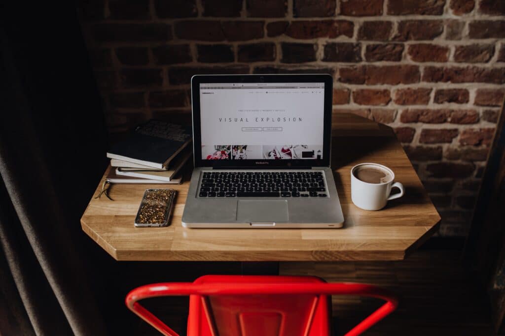 bureau bois avec ordinateur portable ouvert, tasse de café et téléphone, chaise rouge