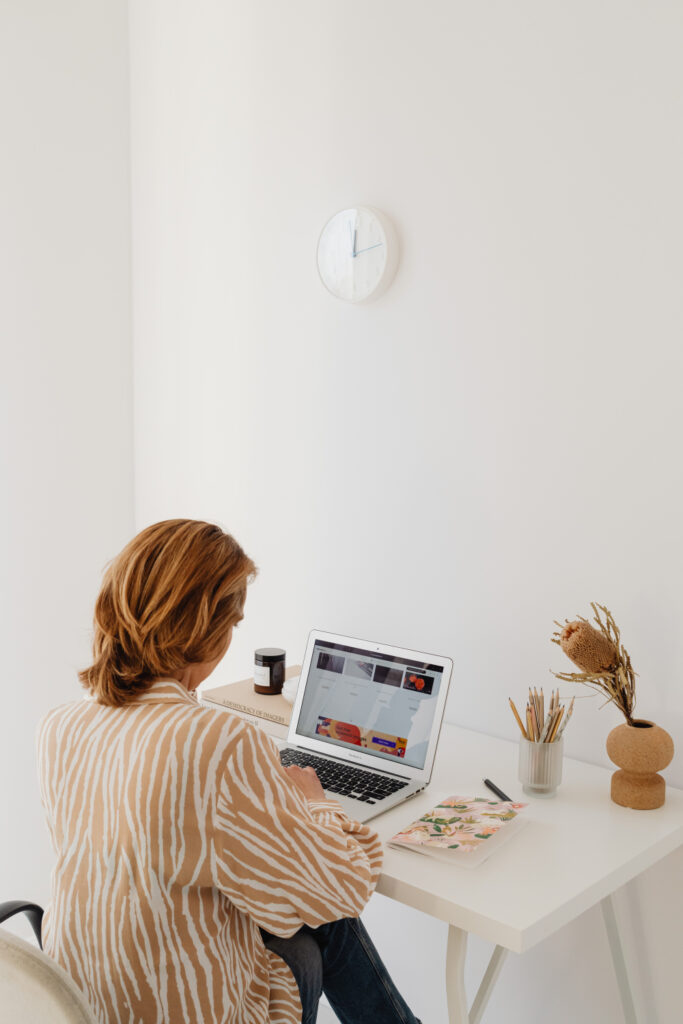 femme de dos assise qui travaille sur son ordinateur portable