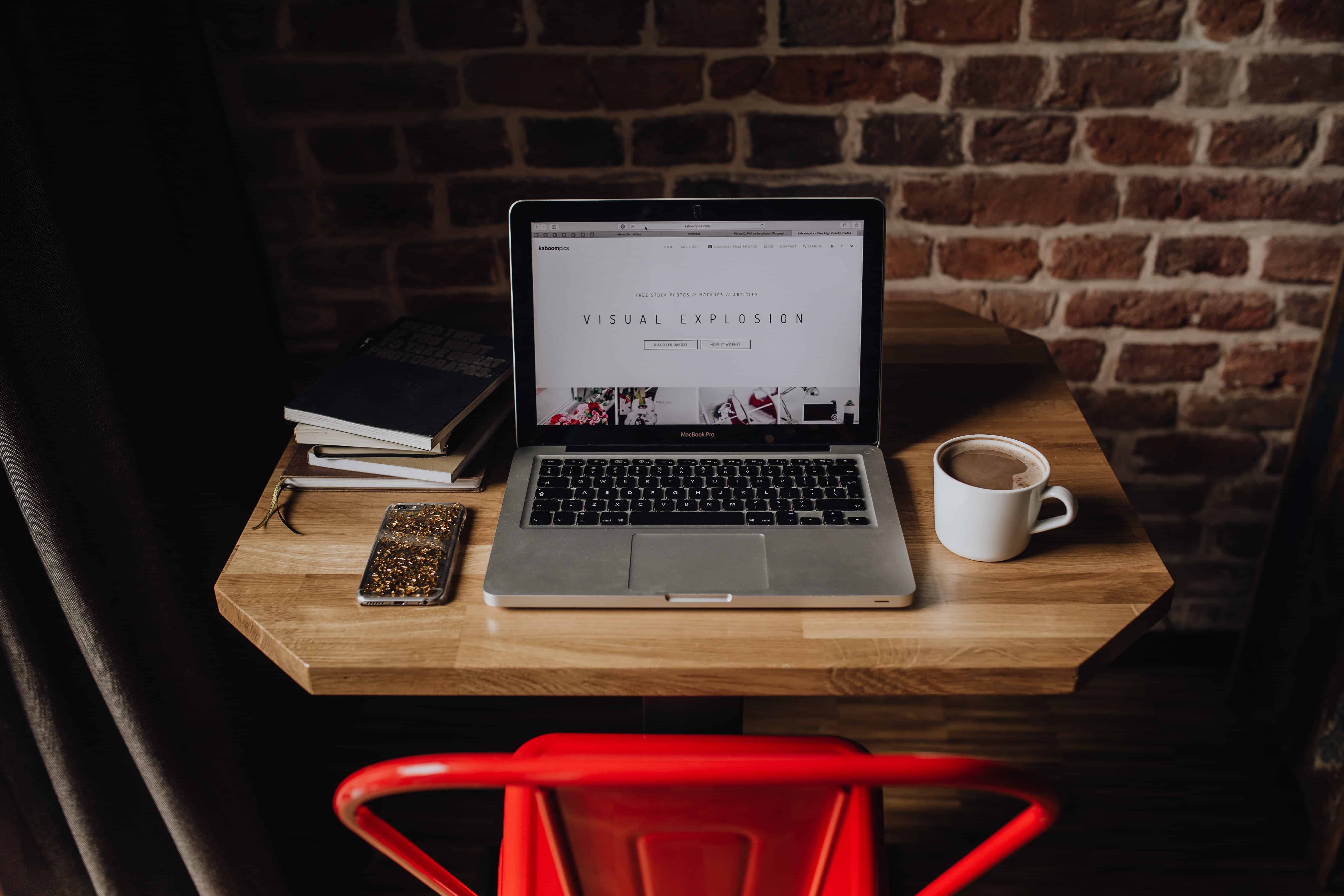 bureau bois avec ordinateur portable ouvert, tasse de café et téléphone, chaise rouge