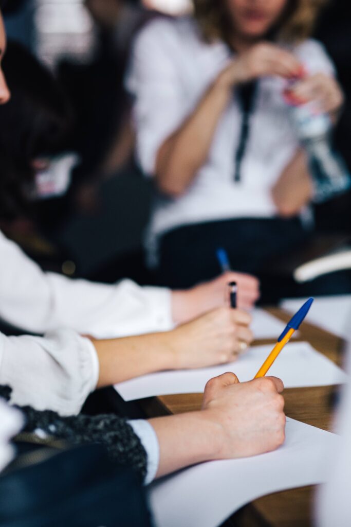 mains de deux personnes prenant des notes avec un stylo